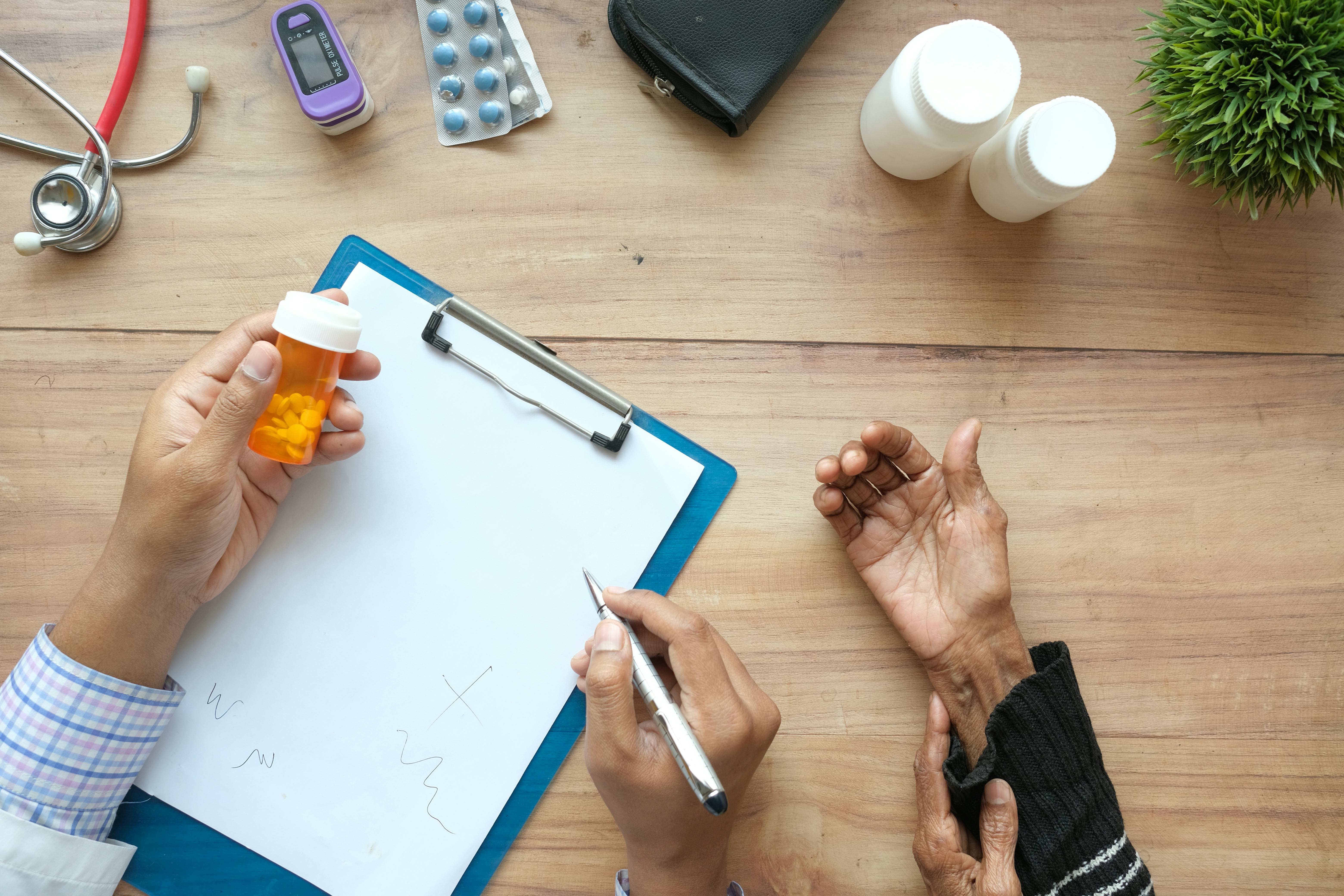 Hands filling out a delivery clipboard next to a medicine bottle